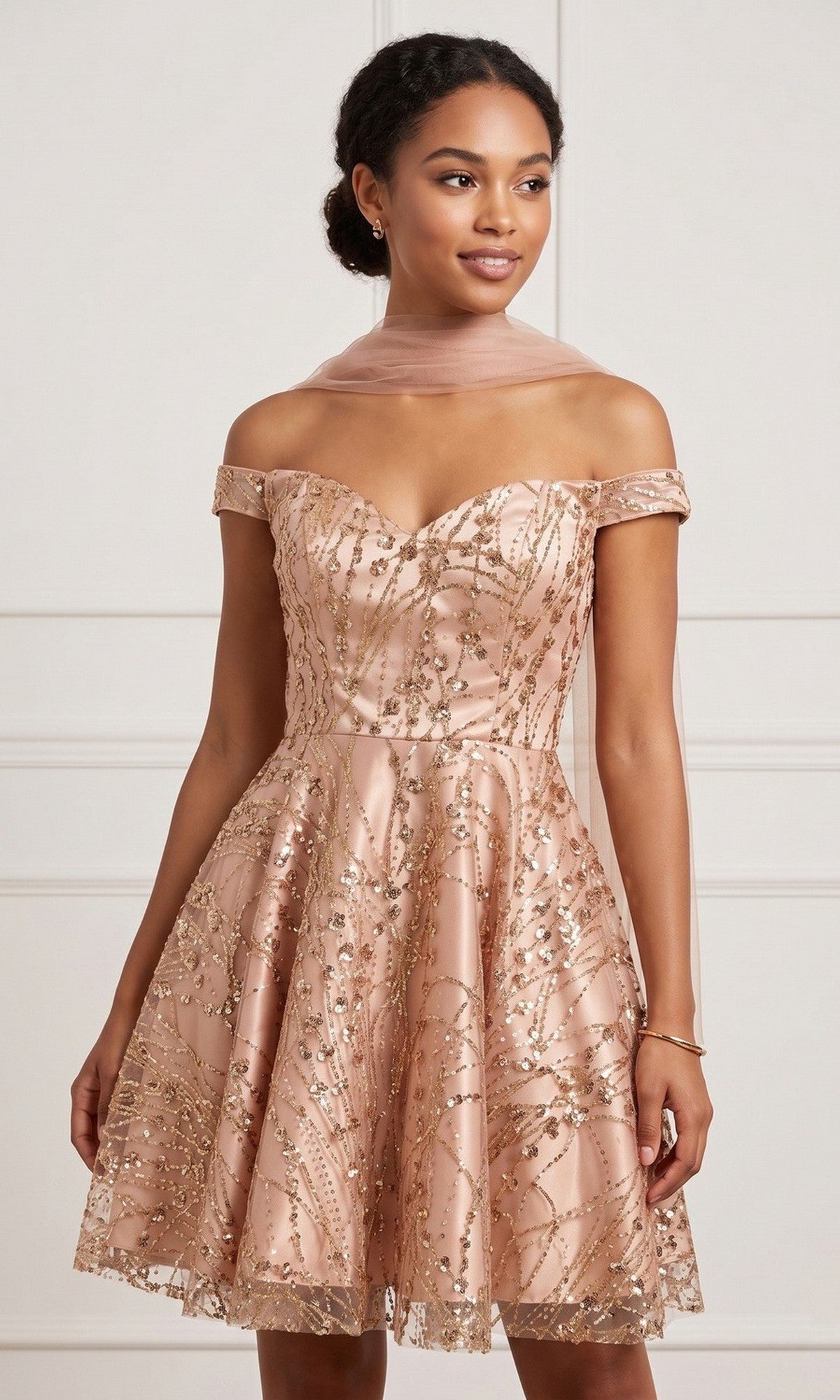 A woman wearing the Short Homecoming Dress: Chicas 4021 in rose—a knee-length, off-the-shoulder dress featuring a sweetheart neckline, gold sequin embellishments, and a sheer pink scarf—stands against a light background.